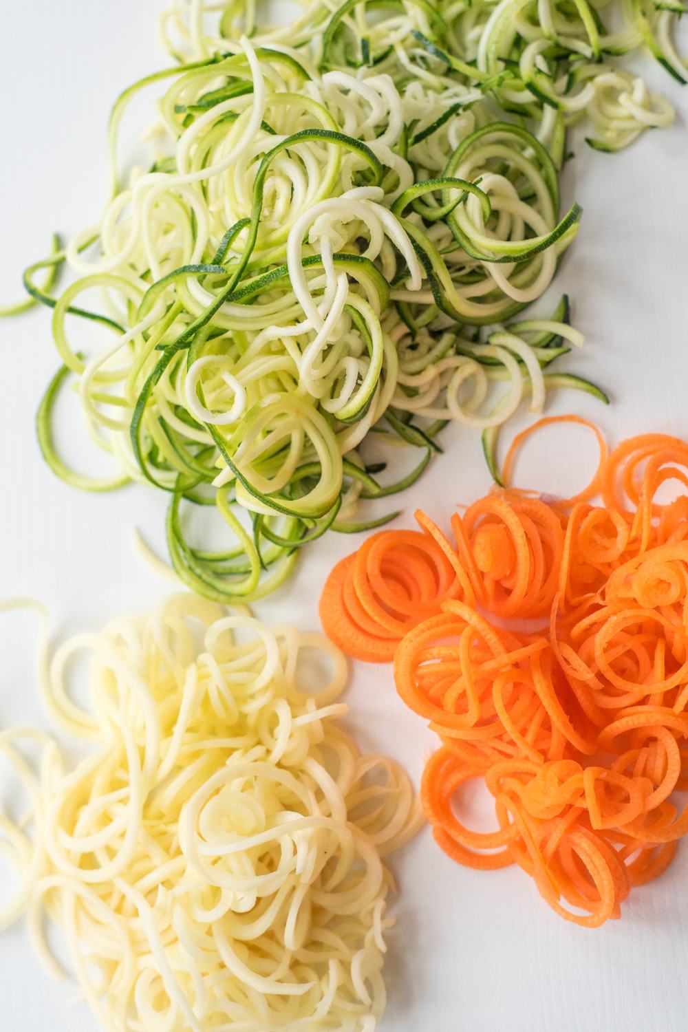 Top down view of spiralized vegetables on a white background