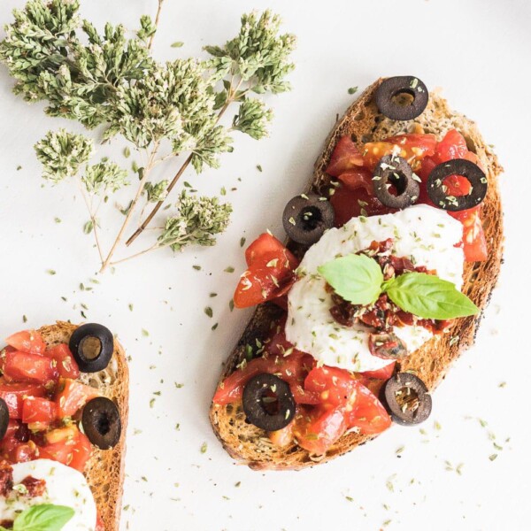 This perfect grilled bruschetta with mozzarella and tomatoes recipe will make your summer BBQ special! Grilled smoky bread, delicious sun-ripened tomatoes, sun-dried tomatoes, extra virgin olive oil, delicious mozzarella and black olives make this the ultimate appetizer for your summer parties!