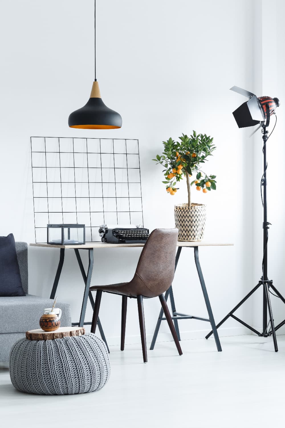 View of a modern office with a leather chair and a small orange tree on a wooden desk: the perfect corner to make money from home.