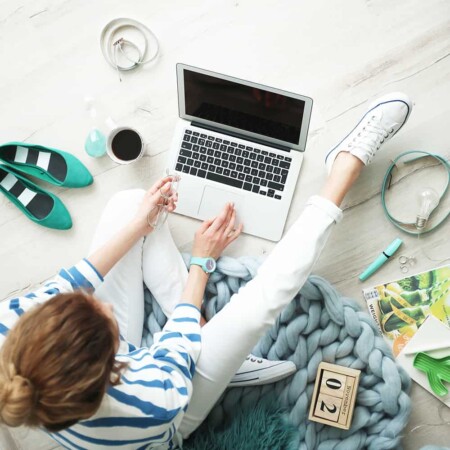 Woman sitting on the floor typing on a laptop.