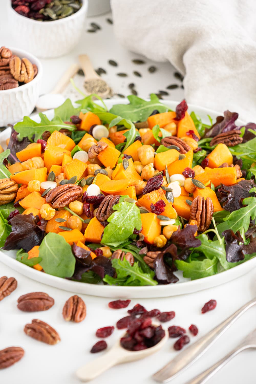 3/4 view of roasted butternut squash salad with arugula, pecans and dried cranberries