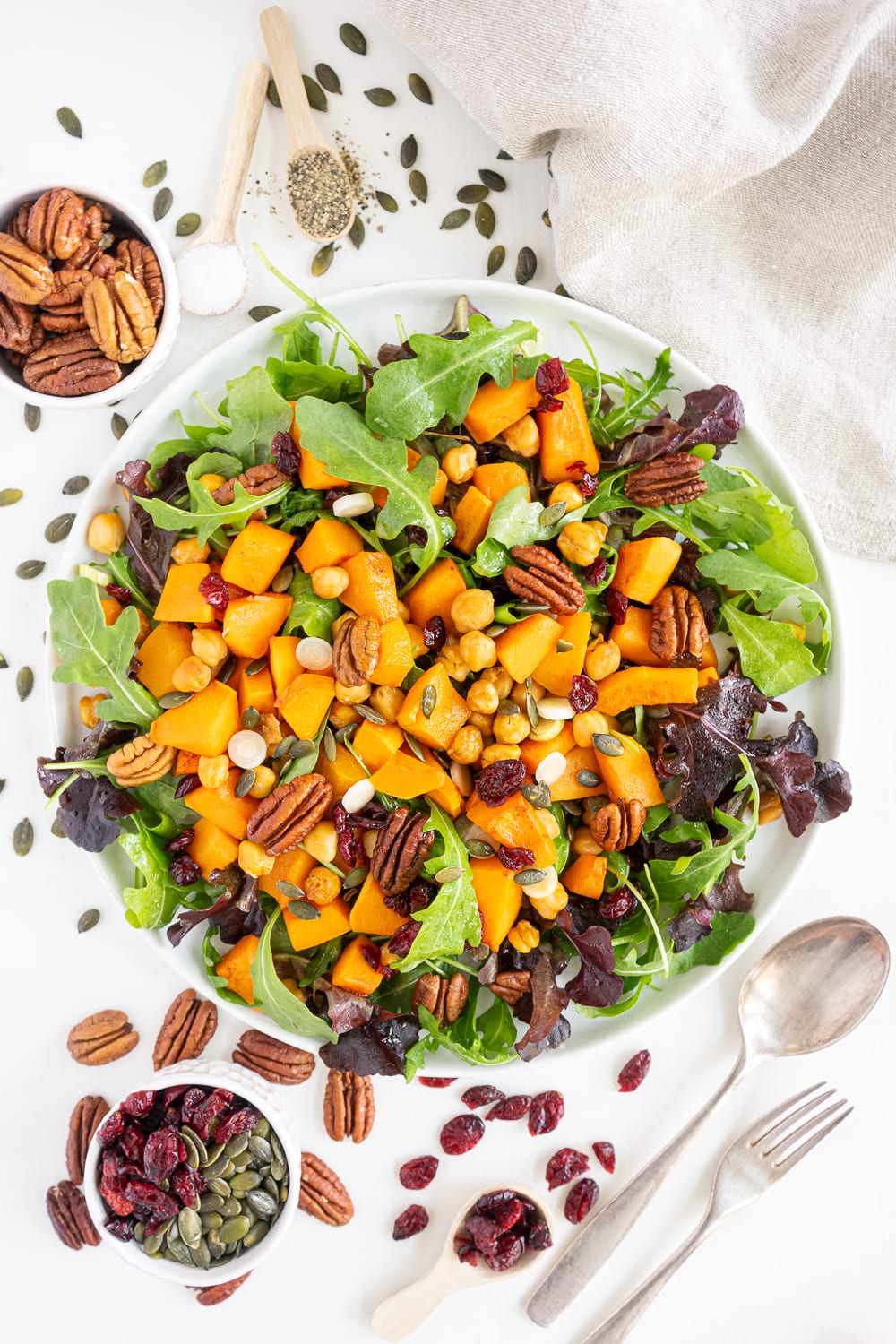 Top view of roasted butternut squash salad with arugula, pecans and dried cranberries