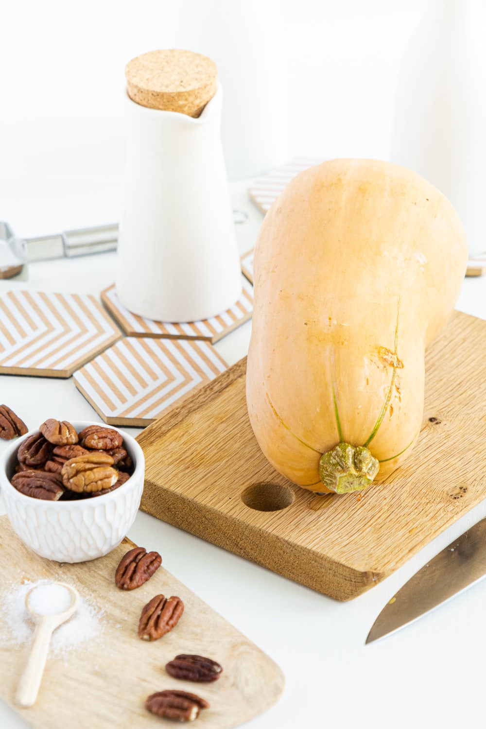 3/4 view of butternut squash on a cutting board with white background