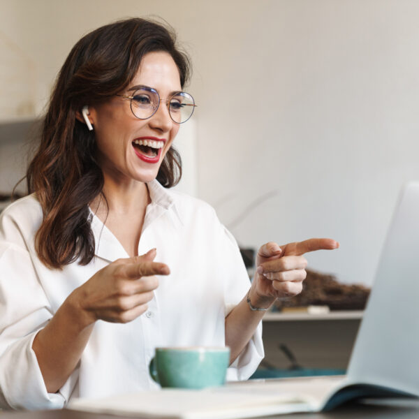 Woman looking happy while working from home and talking to someone on her laptop
