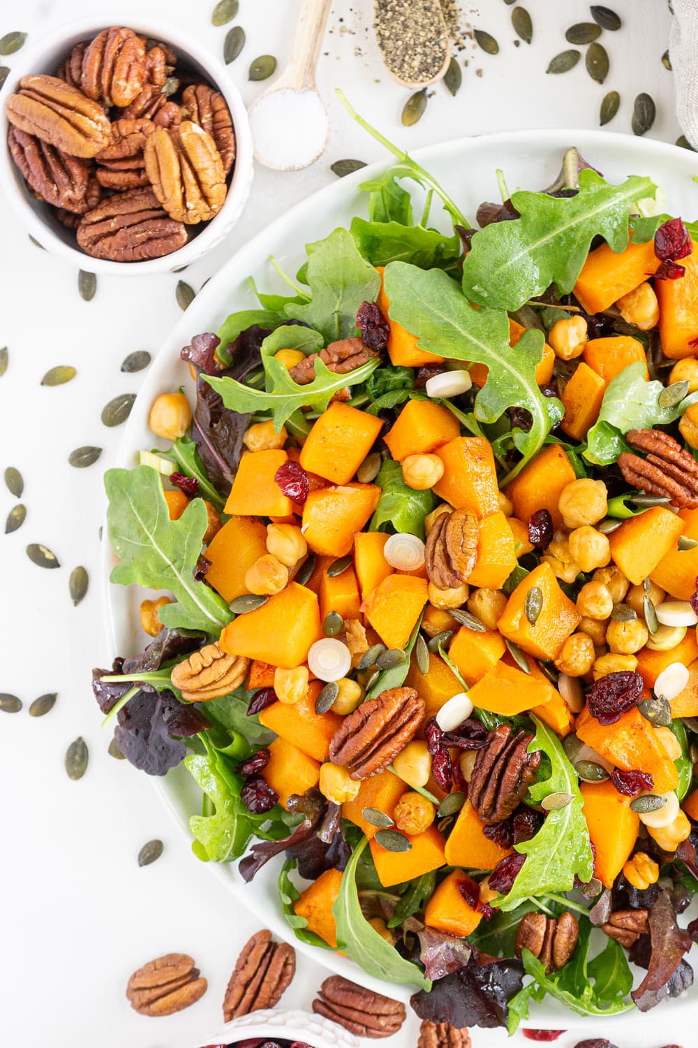 Top view of roasted butternut squash salad with arugula, pecans and dried cranberries