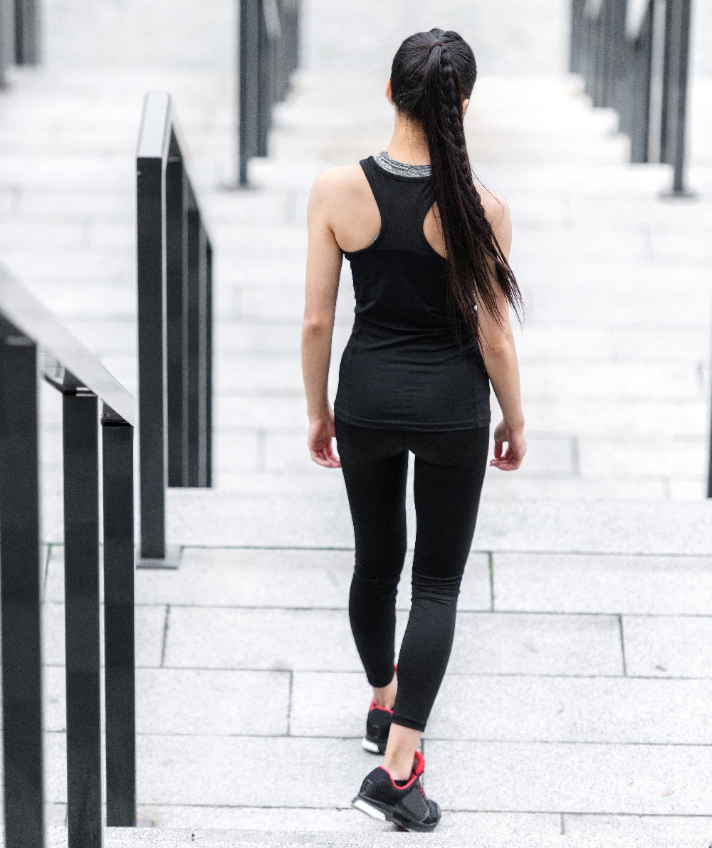 Woman walking down some stairs in gym clothes, making money while using the sweatcoin app