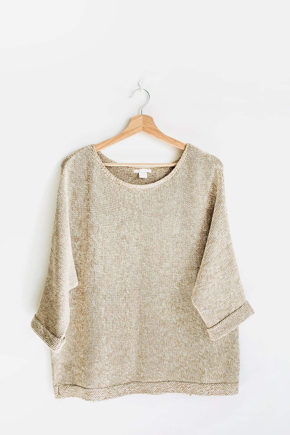 Beige jumper on a wood hanger on white background