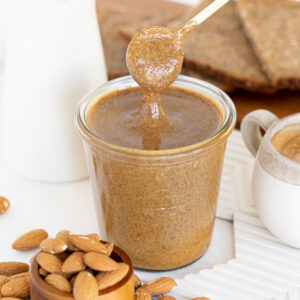 Spoon dipped in a glass jar filled with almond butter