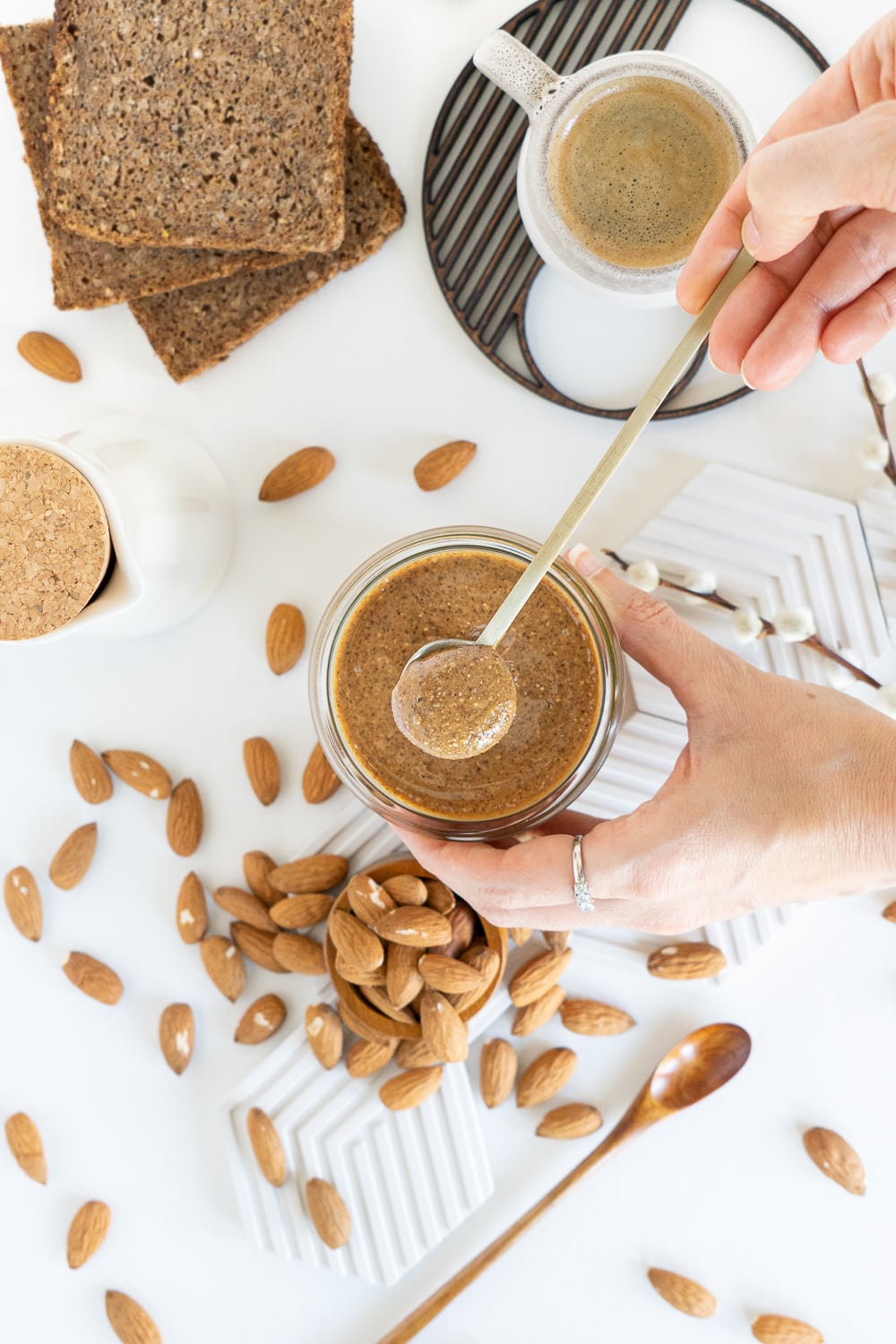 Hands holding almond butter jar with a spoon top view