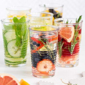 A picture of 6 glasses with infused water of different flavours on white background.