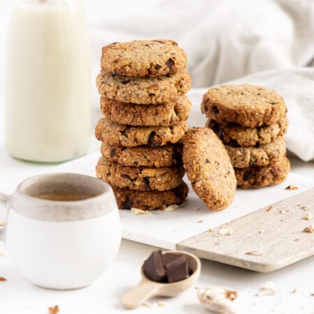 Side view of a pile of breakfast cookies with coffe and milk