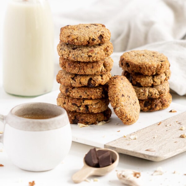 Side view of a pile of breakfast cookies with coffe and milk