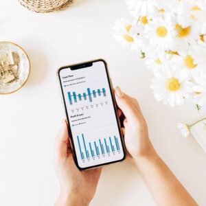 A woman holding a mobile phone using a budgeting app to track expenses