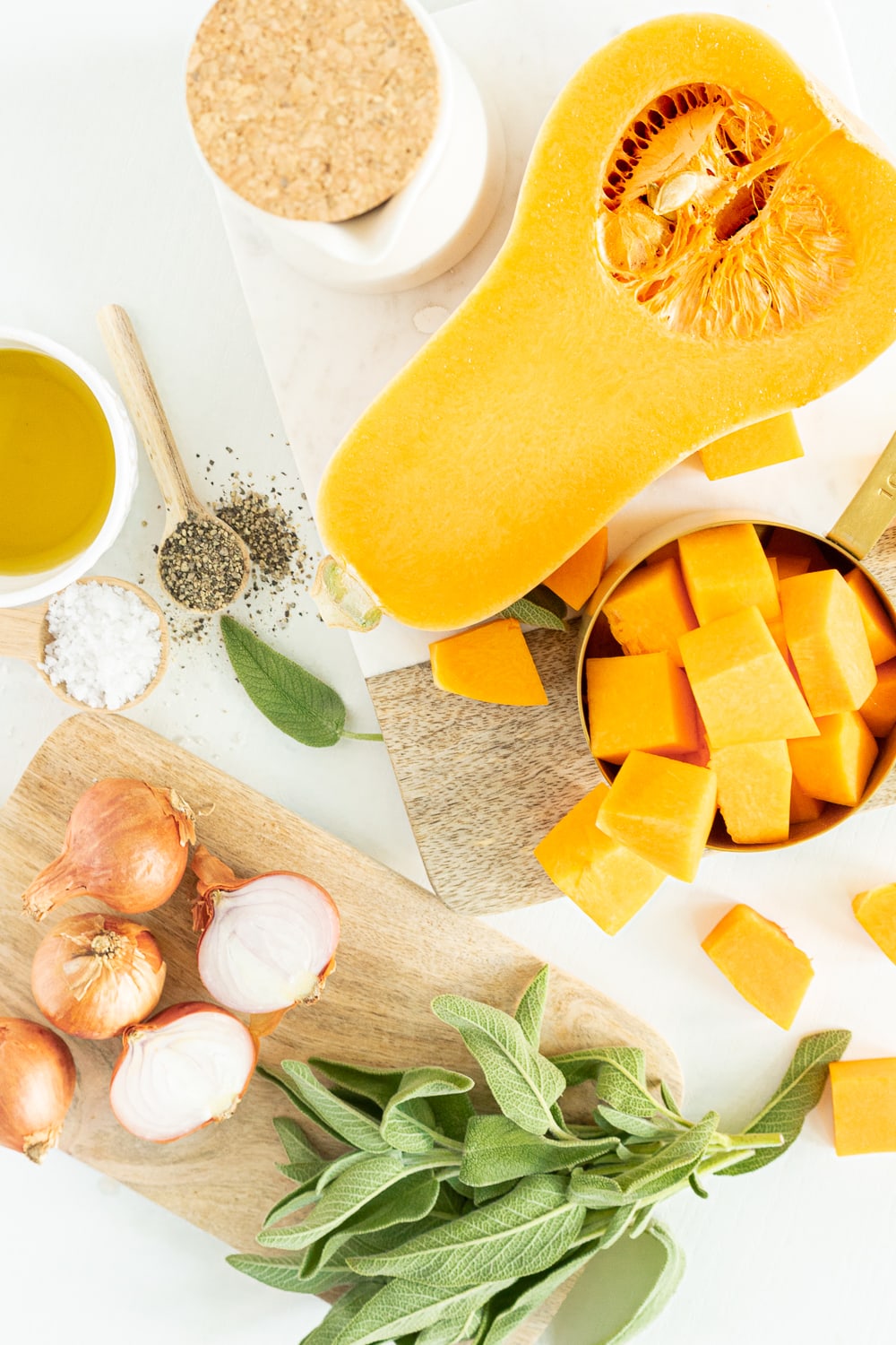 top view of ingredients needed to make butternut squash pasta with sage: onions, butternut squash, sage, pepper, olive oil, salt