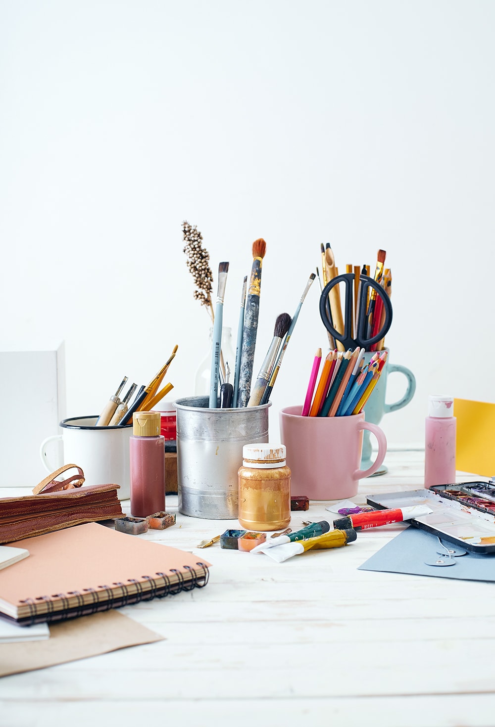 Art supplies on a desk including pencils. brushes, paper