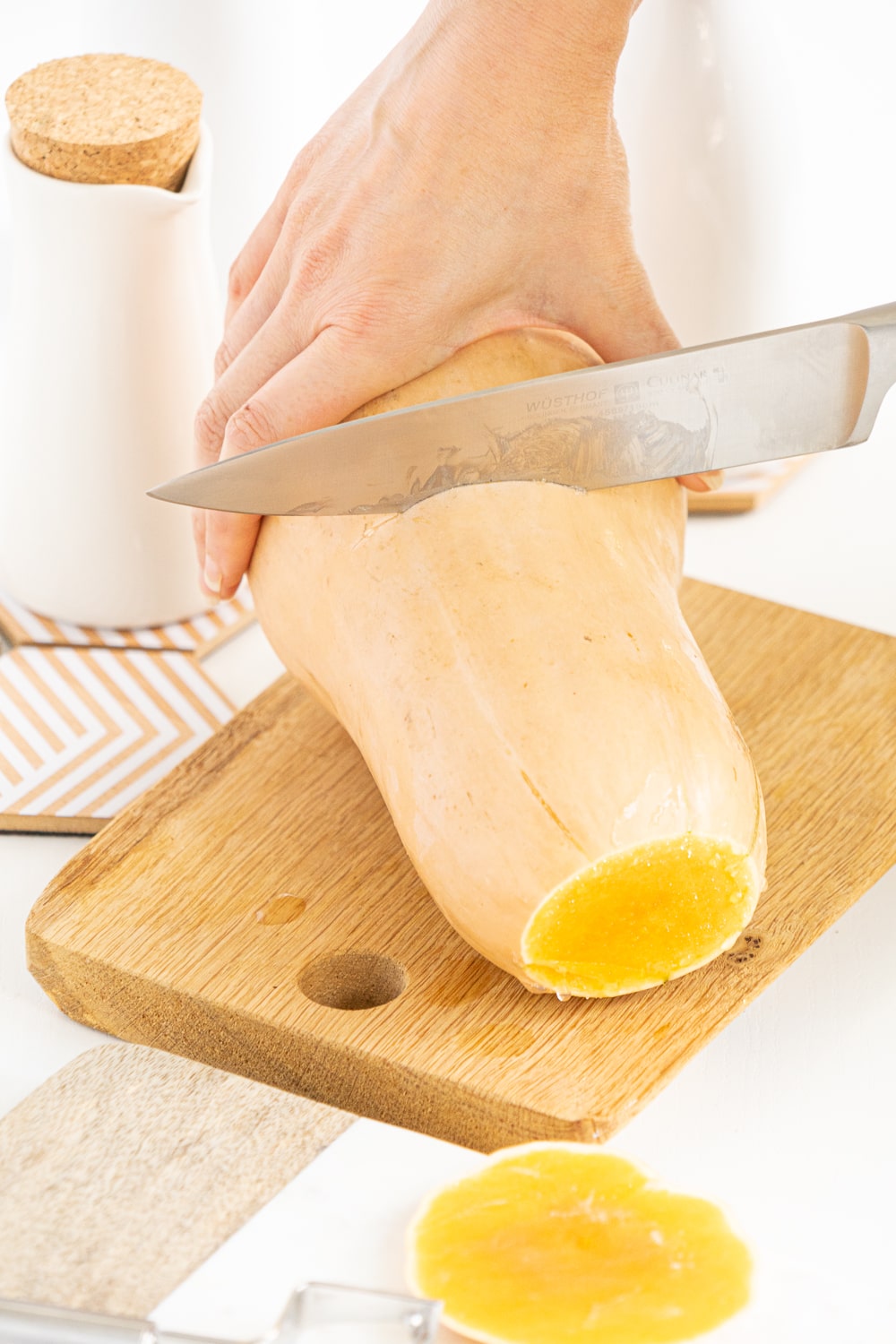 Hands cutting a large butternut squash in half using a knife