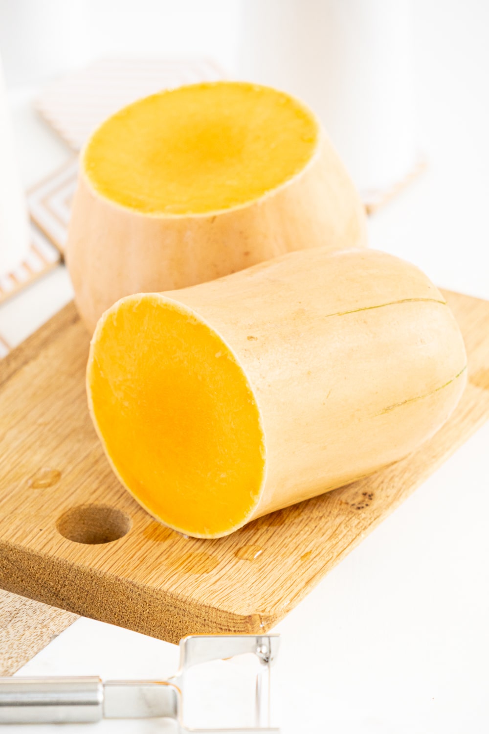 Butternut squash cut in half on a cutting board