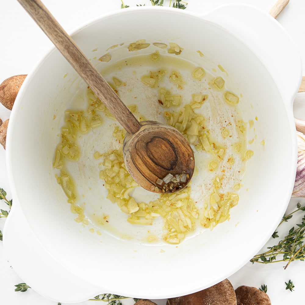 Top view of white pot with olive oil and onion frying