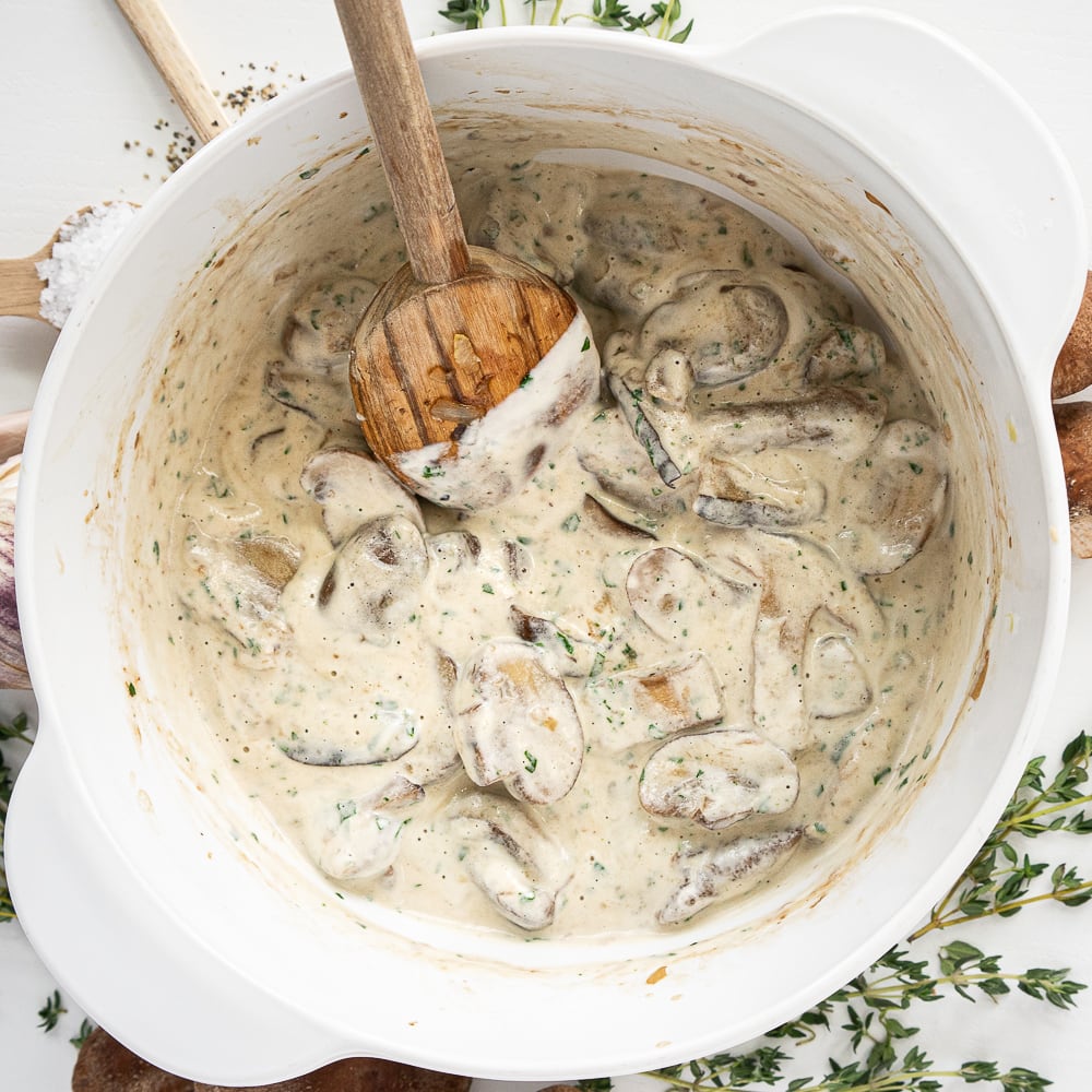 Top view of white pot with cooked mushrooms and cashew cream