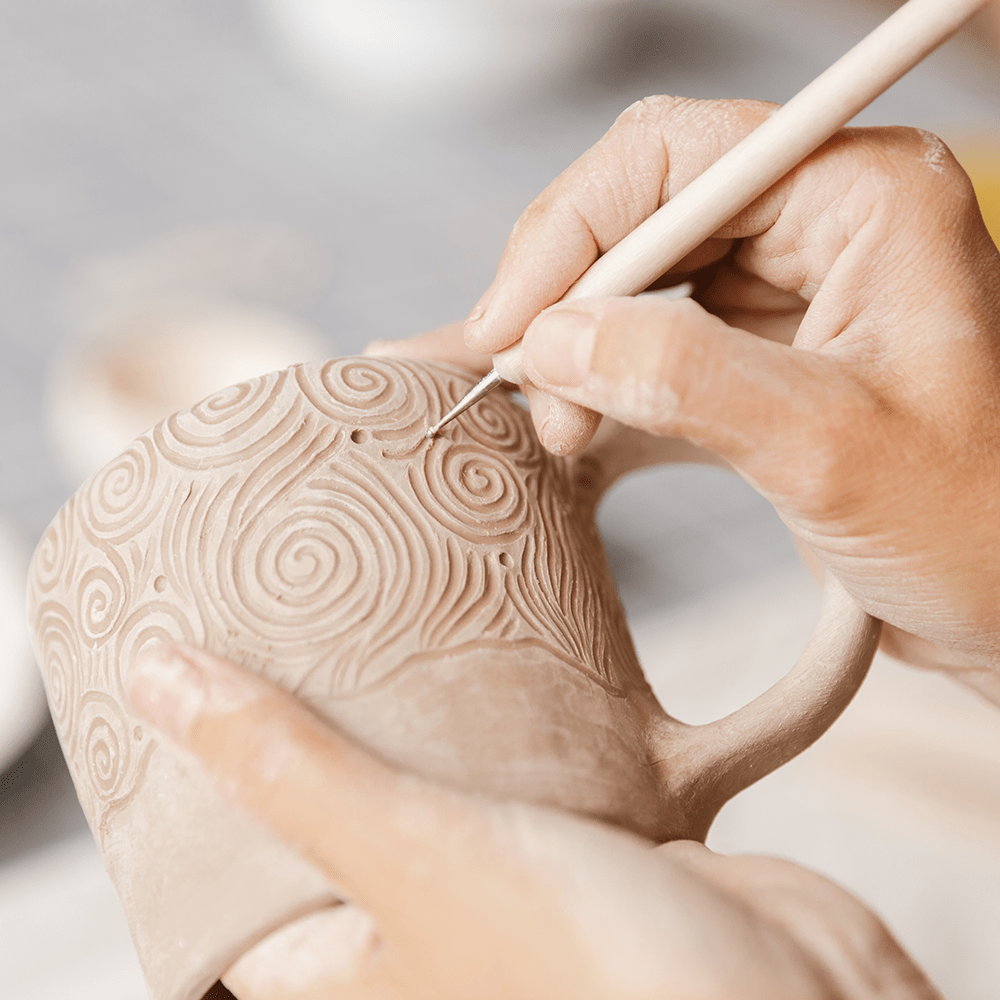 hands decorating a ceramic mug