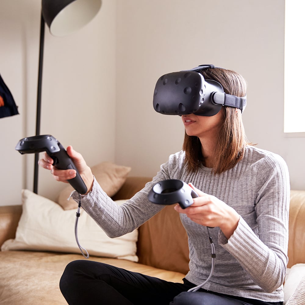 Mujer jugando al juego de realidad virtual mientras sostiene 2 consolas