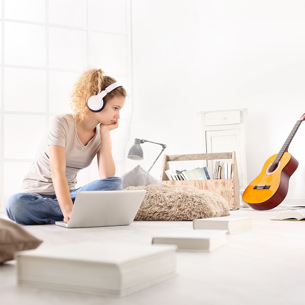 Mujer escuchando música con auriculares mientras está en su laptopo