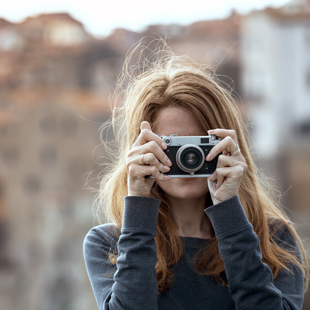 Mujer tomando una foto con una cámara vintage