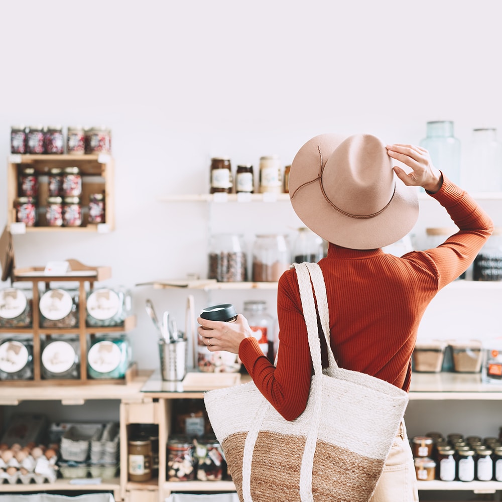Mujer sosteniendo su sombrero mientras ve los productos en la tienda