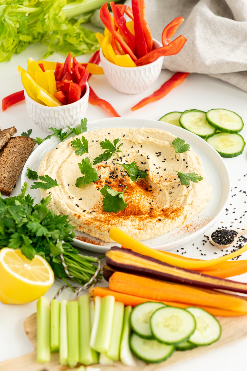 Plate with homemade hummus surrounded by veggies