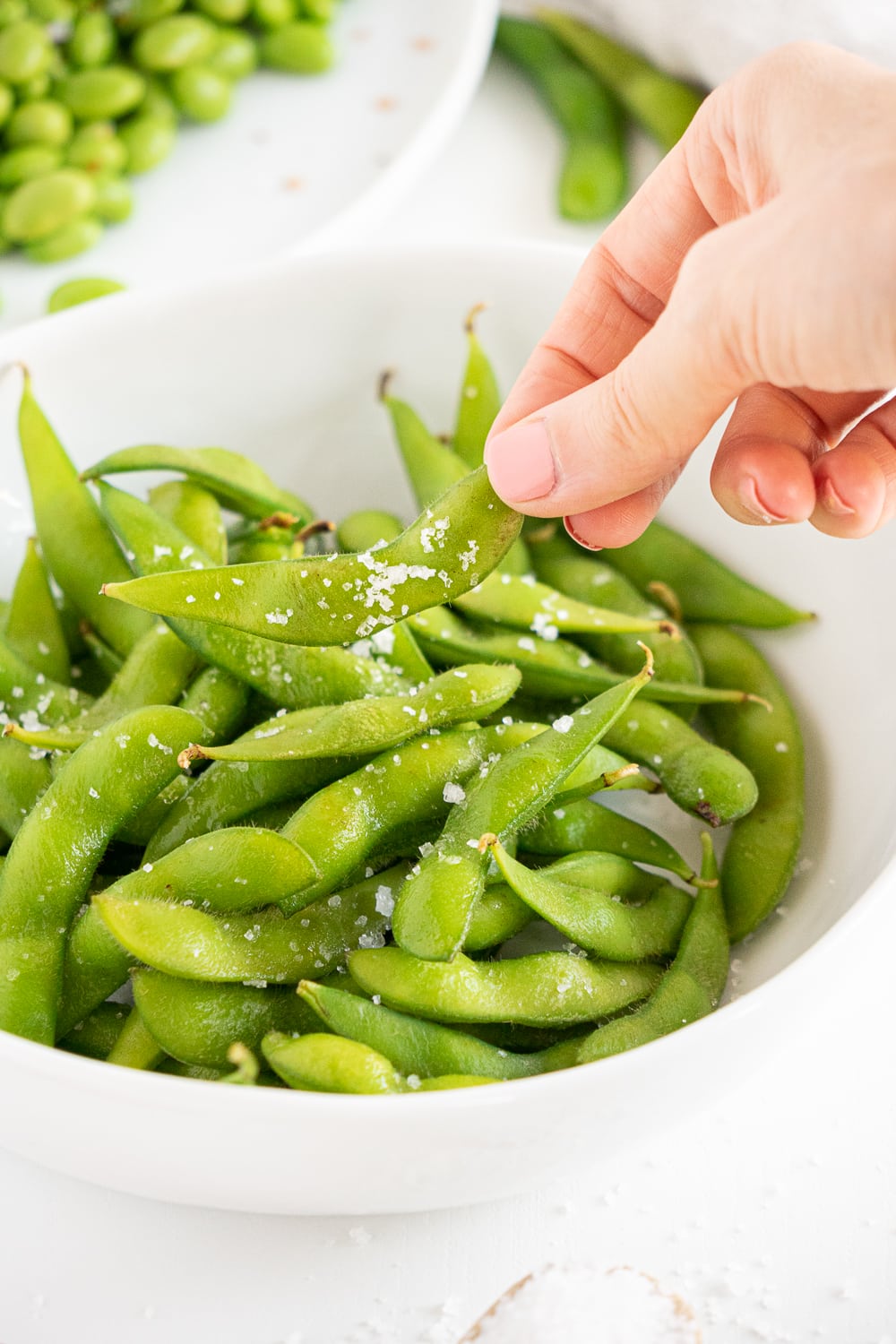 Hand reaching for some edamame beans