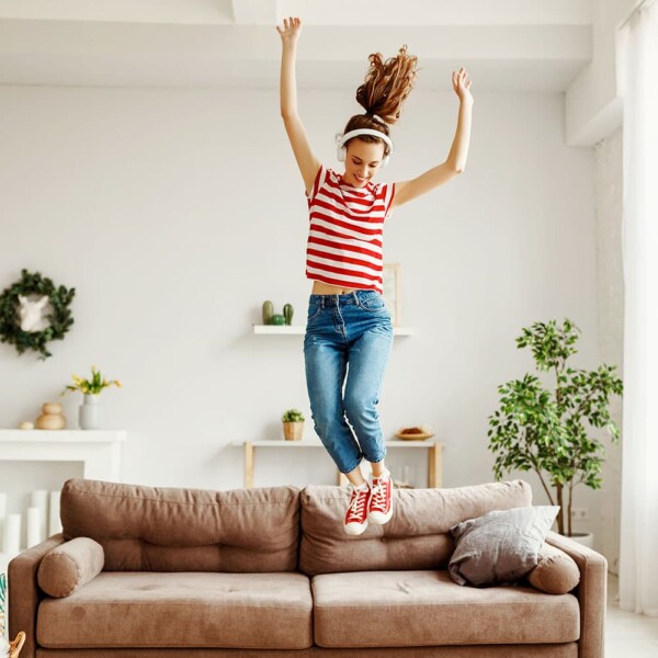 Woman jumping on a sofa happy to find out how to make $1000 a month