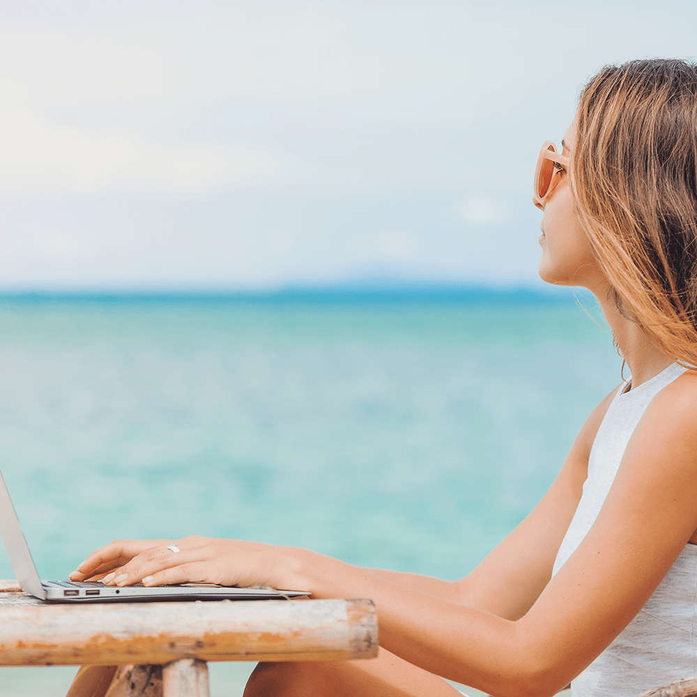 Travel planner working on the beach with her laptop