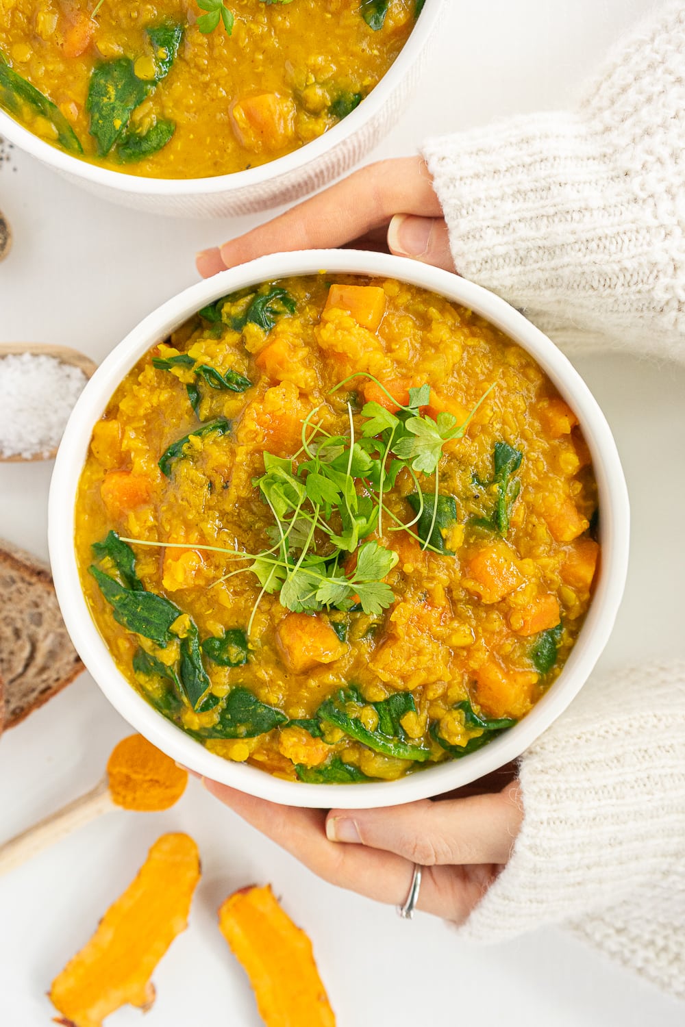 Hands holding a warm bowl of red lentil soup