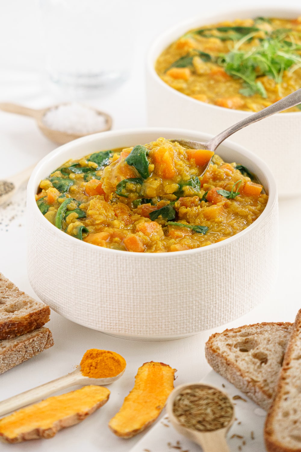 Spoon holding some red lentil soup from a bowl