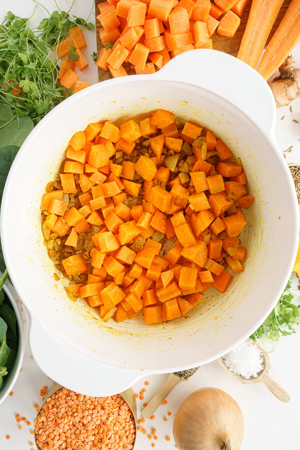 Overhead shot of white pot with carrots and spices