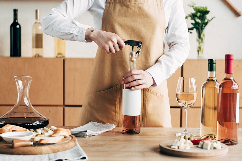 A photo of a man opening a bottle of wine as an example of the top stock photos to sell online
