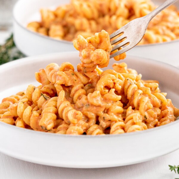 Plate with a fork full of vegan creamy tomato pasta