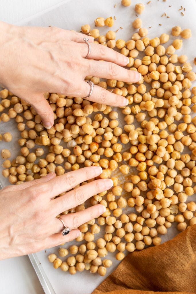 Hands mixing chickpeas with olive oil