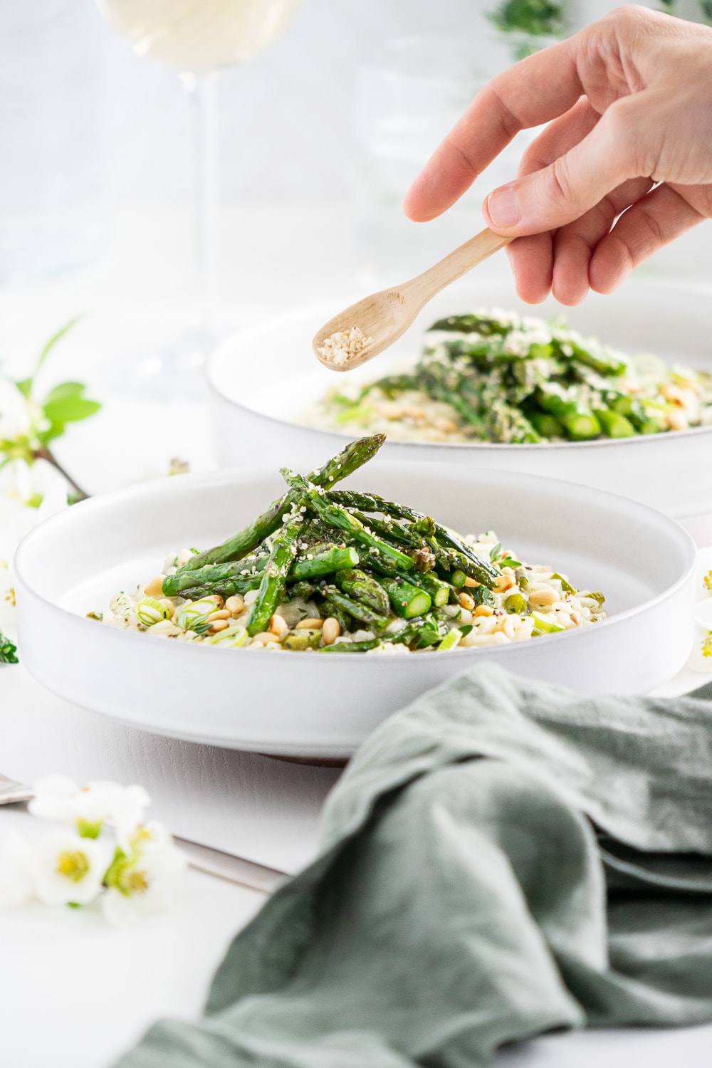 Hand putting vegan parmesan on asparagus risotto