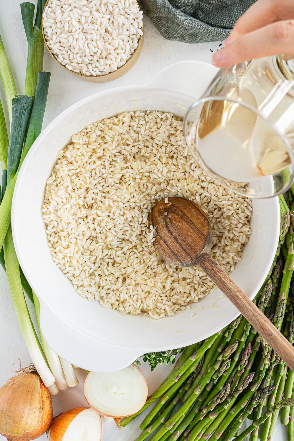 Hand pouring wine from a glass into the rice