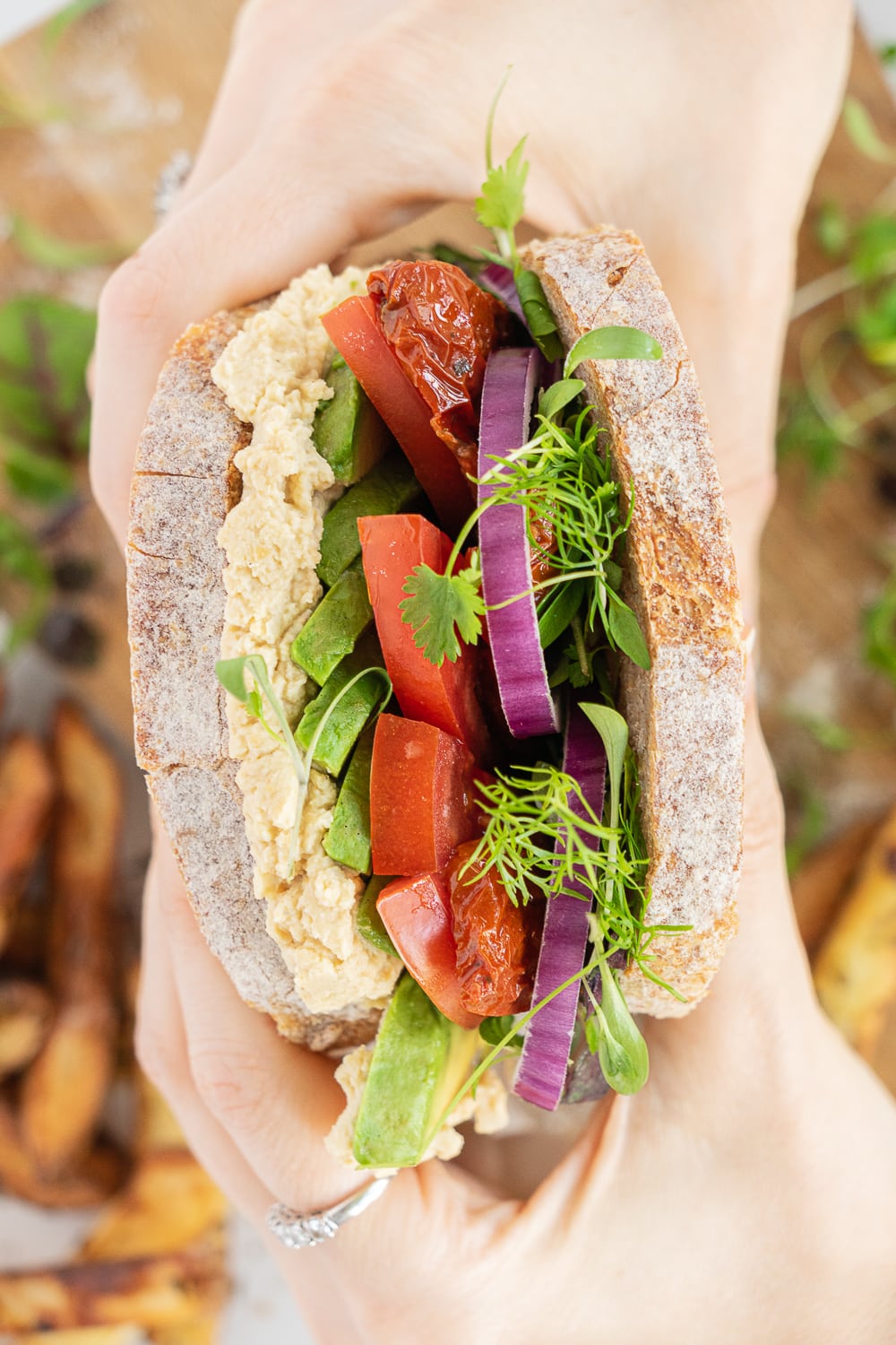 Hands holding an avocado sandwich