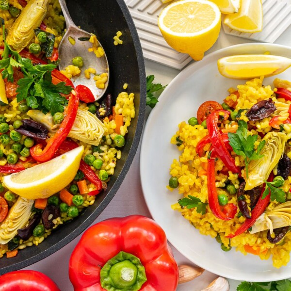 Top view of a plate and a pan filled with vegetarian paella