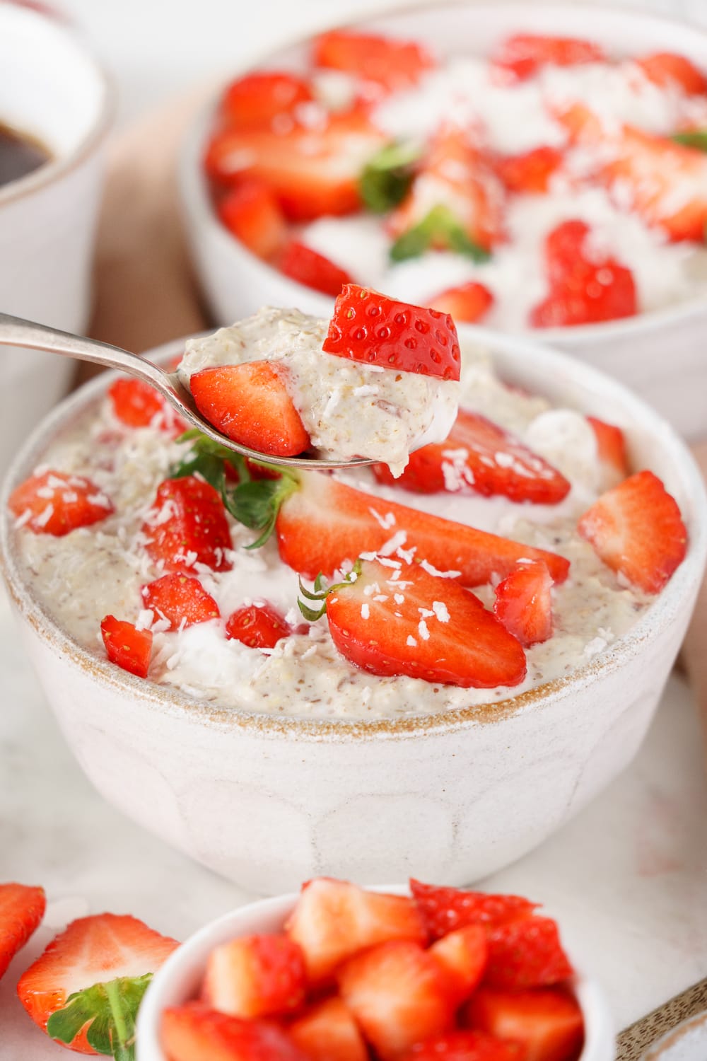 Spoon digging into a bowl filled with strawberry overnight oats