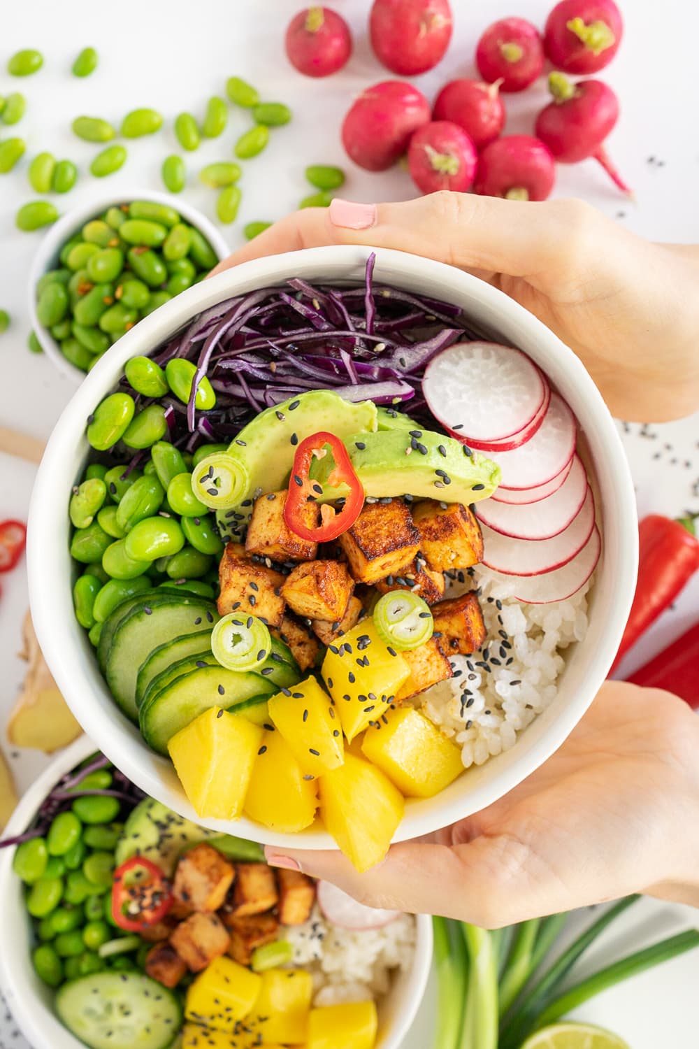 Hands holding a vegan poke bowl