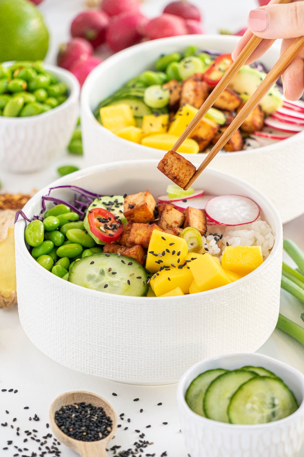 Chopsticks holding a piece of crispy tofu from a poke bowl