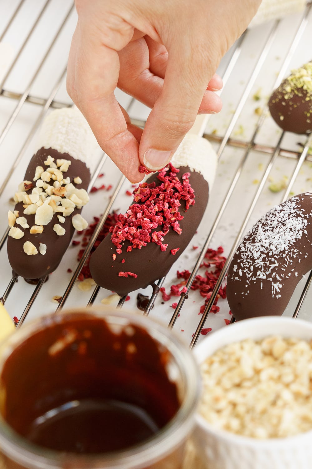 hand adding toppings on a chocolate banana