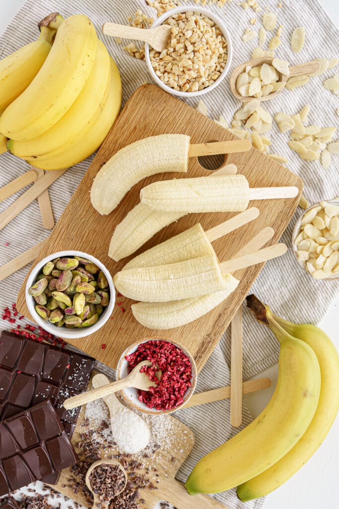 6 bananas on a wooden board with popsicle sticks