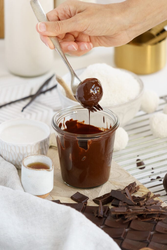 lifting coconut ball from melted chocolate with a fork