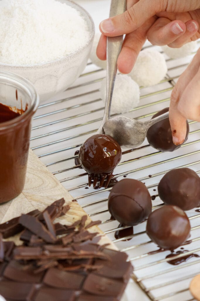 placing coconut ball covered in chocolate to dry on a tray