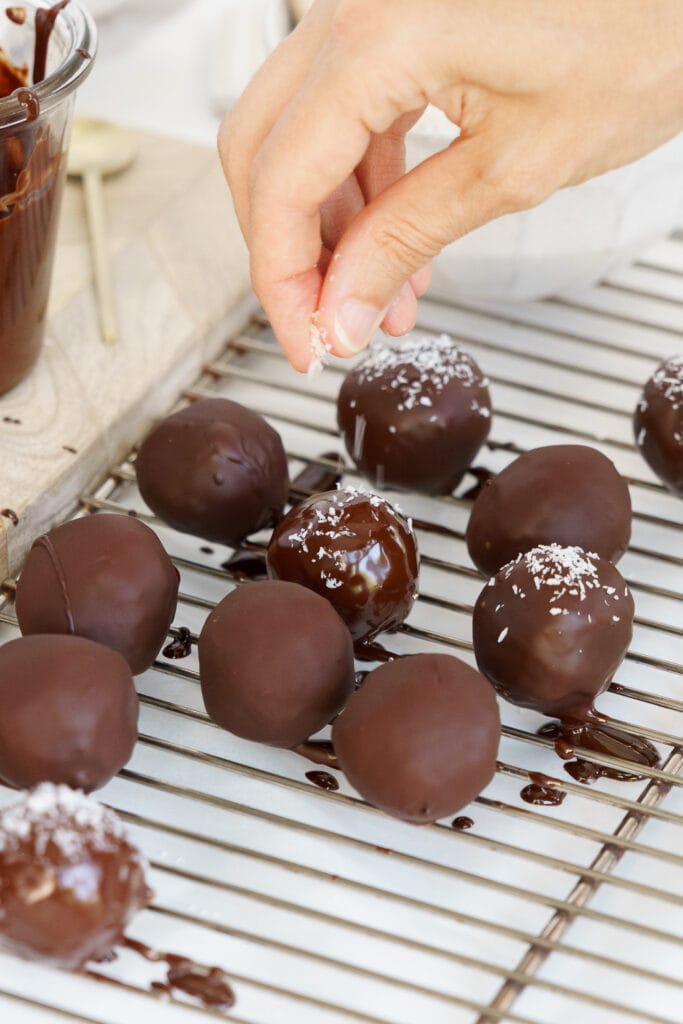 adding some shredded coconut on top of bounty balls before the chocolate hardens
